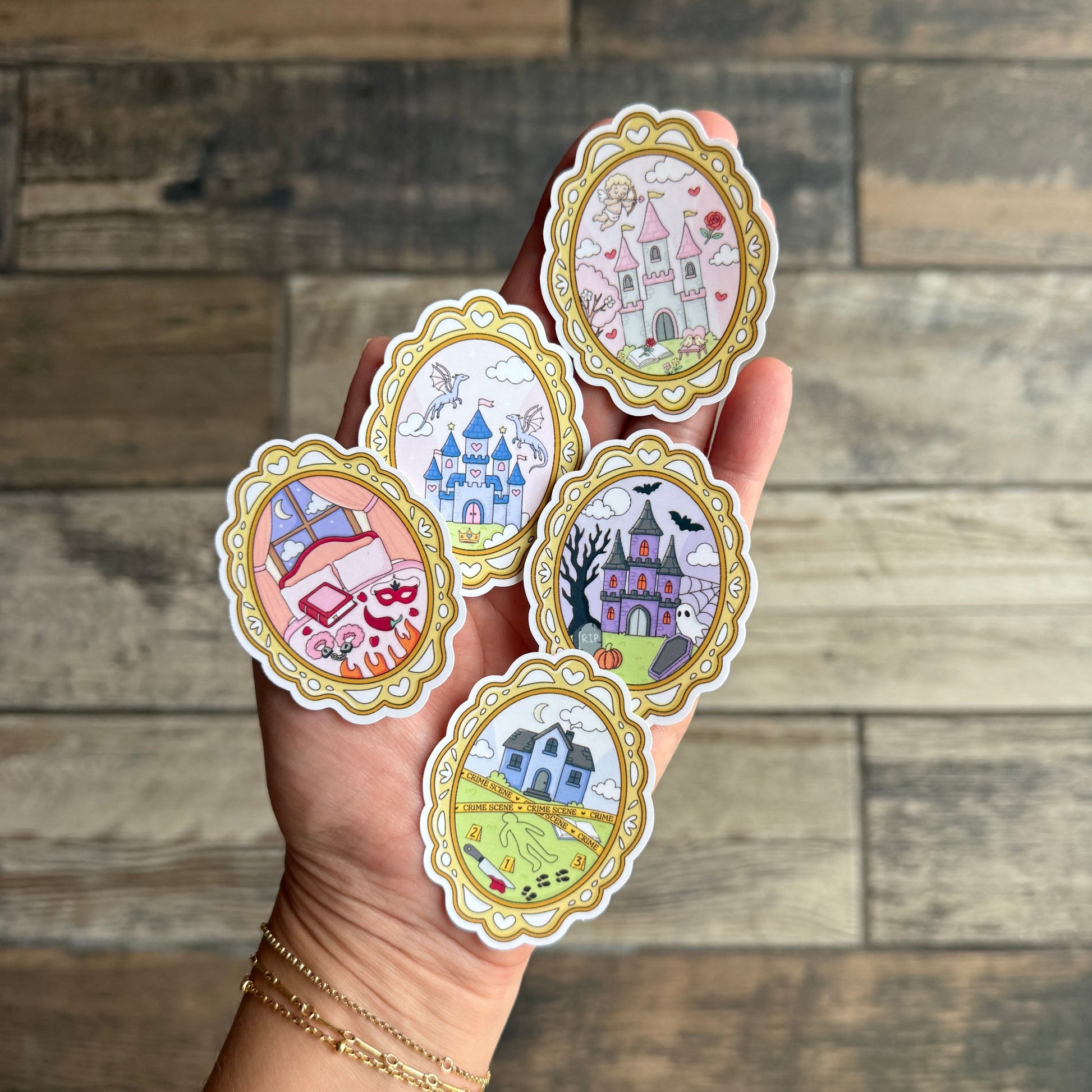Hand holding five decorative stickers with intricate designs against a wooden background